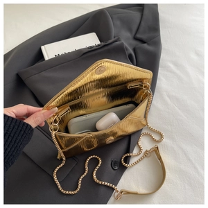 Detailed interior of a gold pleated envelope bag showing space for phone and earbuds