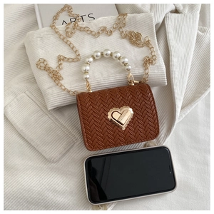 Detailed macro view of small brown woven bag with pearl handle and heart-shaped gold lock