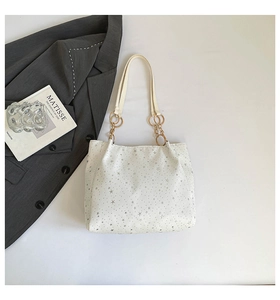 Close-up of white tote bag with silver star prints and golden ring chain details