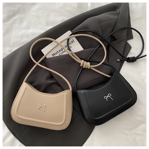 Detail of minimalist underarm bags with metal bows and stylish knotted shoulder straps