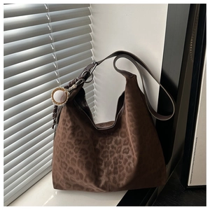 Detail of leopard print tote bag with suede texture and baseball charm on a side strap