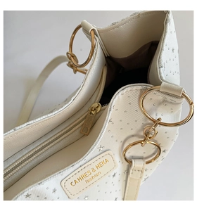 Detail of white PU leather tote showing star patterns, golden hardware and zipper closure