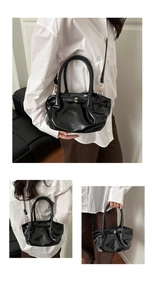 Detail of black pleated bucket bag with gold magnetic clasp and glossy PU leather texture