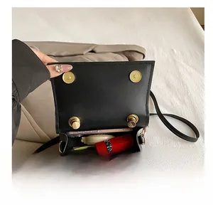 Close-up of small black crossbody bag interior with phone, lipstick, and eyeglasses