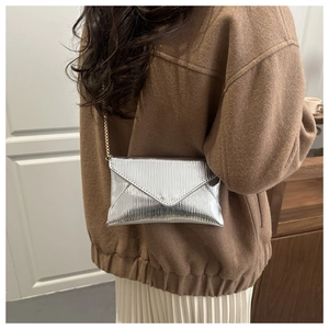 Detail of silver envelope bag featuring embossed water ripple texture and chain strap