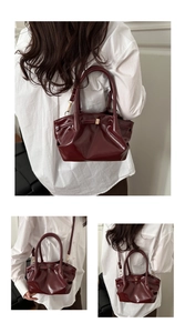 Macro detail of burgundy cloud bucket bag with glossy finish and gold buckle hardware