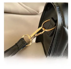 Macro detail of high-quality light gold metal hook and leather texture on a black bag