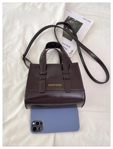 Detail of dark brown faux leather tote bag with FASHION & BAGS logo and strap