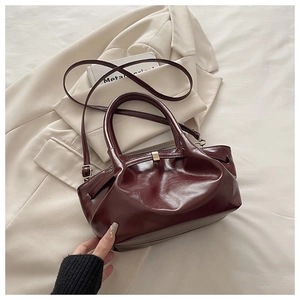 Detail of burgundy glossy patent leather bucket bag with cloud-like pleats and gold hardware