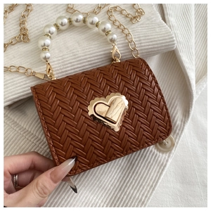 Detailed view of woven brown handbag featuring pearl handle and gold heart lock
