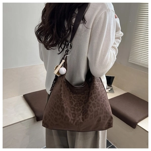 Detail of leopard print tote bag with baseball charm on model in soft natural light