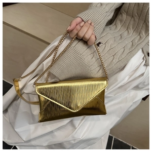Chic gold envelope bag with wavy texture and fine metal chain strap shown by a model