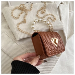 Close-up of brown woven texture bag featuring golden heart lock and pearl handle