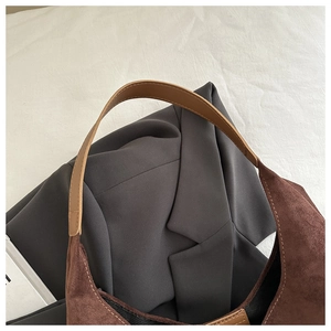 Detail of the brown faux suede texture and leather strap on a minimalist shoulder bag