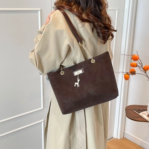 Brown matte suede tote bag with deer charm and chain strap shown on a model