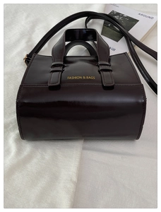 Macro detail of dark glossy leather tote bag showing fine texture and golden logo