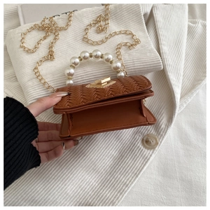 Detail of brown woven leather bag with pearl handle and gold chain strap close-up