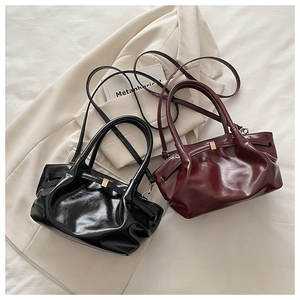 Detail view of stylish cloud bucket bags in black and burgundy with gold buckles