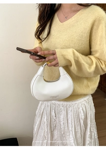 Borsa hobo bianca lucida con dettagli dorati indossata a spalla da una modella