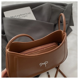 Detailed interior of brown leather shoulder bag with a zipper pocket and metal bow