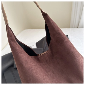Detail of a large dark brown suede tote bag with a minimalist wide shoulder strap design