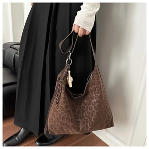 Detail of leopard print tote bag featuring suede texture and decorative tassel on strap