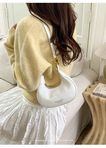 Borsa sottobraccio bianca a mezzaluna indossata da modella con maglione giallo