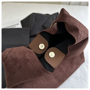 Detail of brown suede bucket bag featuring dual vintage metal magnetic closures