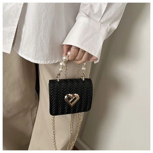 Detail of a mini black woven bag with gold heart lock and elegant pearl handle strap