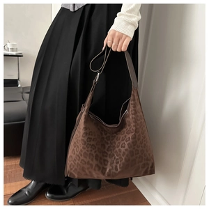 Detail shot of leopard print hobo bag showing textured fabric and brown leather strap