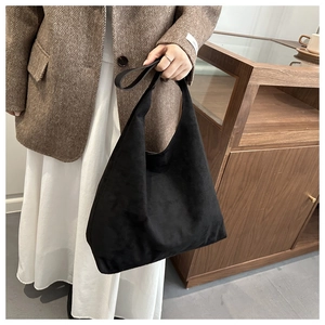 Close-up of minimalist black suede hobo shoulder bag with seamless wide strap