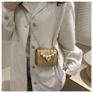 Detail of woven texture mini bag with pearl handle and heart lock on white coat