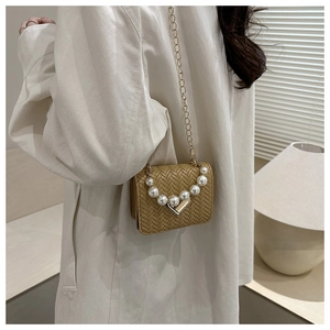Detail of woven texture shoulder bag with pearl handle and metallic V-shaped clasp