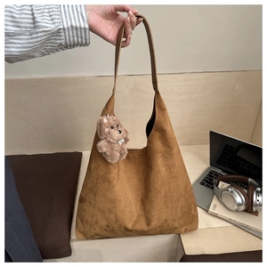 Detail view of brown suede tote bag with cute plush bear charm and matching shoulder strap