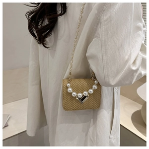Chic woven mini crossbody bag with pearl handle and gold heart clasp detail