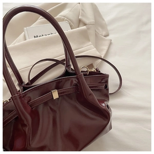 Macro shot of dark wine red glossy leather bucket bag with elegant gold metal buckles