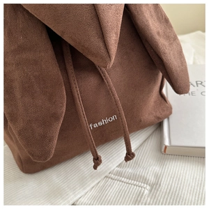 Detail of suede drawstring bag with rabbit ear flap and fashion embroidery detail