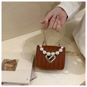 Close-up of brown woven texture bag with pearl handle and golden heart lock