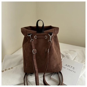 Detailed view of dark brown suede backpack with silver buckles and drawstring closure
