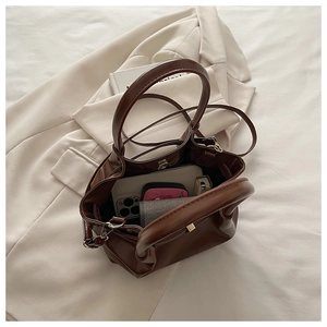 Detail showing the spacious interior of a dark brown crossbody bucket bag with daily items