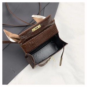 Detail of dark brown croc-embossed handbag with gold clasp and silk scarf decor