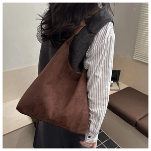 Vista laterale di una borsa hobo marrone scuro in materiale opaco indossata da modella