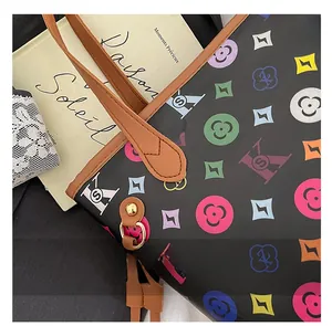 Détail de couture précise sur cabas à logo coloré et anses en cuir marron