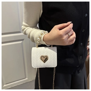 Detail of white woven crossbody bag with gold heart clasp and pearl bead handle
