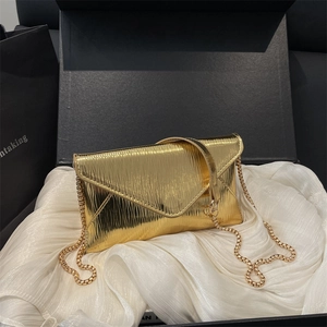Chic gold envelope clutch with vertical pleats and chain strap on white silk background