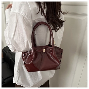 Detail of burgundy bucket bag with pleated design and elegant gold square metal buckle