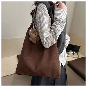 Dettaglio della borsa tote in pelle scamosciata marrone scuro con ciondolo a orsetto