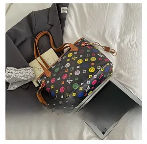 Gros plan d'un sac cabas noir avec motif monogramme coloré et poignées en cuir