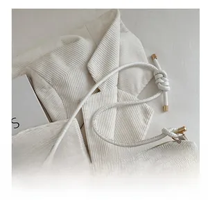 Detail of fabric texture with bow prints and white braided rope strap with gold accents