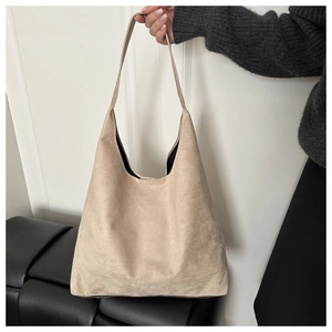 Close-up of a large beige suede shoulder bag featuring a soft structure and premium texture